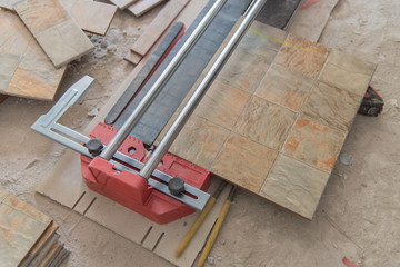 Industrial tiler builder worker working with floor tile cutting equipment at repair renovation work,Worker working on laying of porcelain tiles