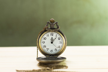 Still life antique clock placed on a wooden floor and a red shotgun shell with human skull on the back.