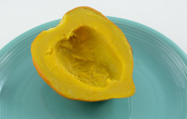 Baked acorn squash half on blue plate with white background