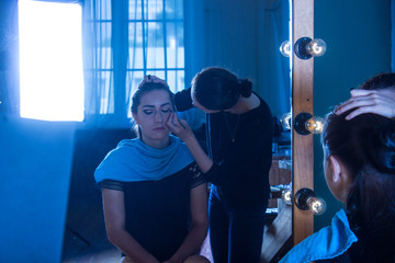 Девушка сидит перед зеркалом для макияжа стиль красота уход за телом подготовка к съемкам  - obrazy, fototapety, plakaty