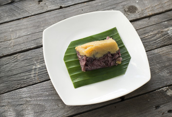 Thai Dessert, sticky rice and egg custard creamy wrapped banana leaf, on a plate,