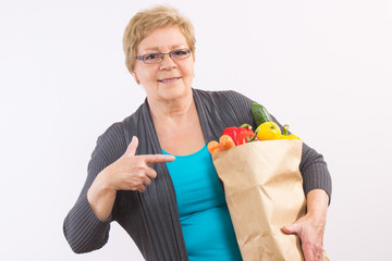 Happy senior woman showing shopping bag with fruits and vegetables, healthy nutrition in old age