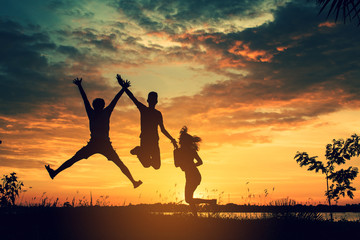 The silhouette of three people jumping with sunset background