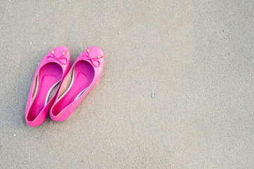 Fototapeta na wymiar Pink feminine shoes on a sandy beach