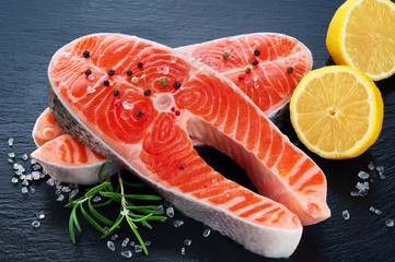 Fresh salmon with lemon and rosemary on a dark background
