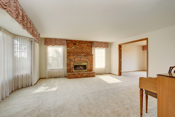 Empty living room interior in light tones with brick fireplace.