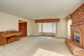 Empty living room interior in light tones with brick fireplace.
