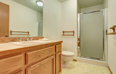 Bathroom interior with wooden vanity cabinet, big mirror and tile floor.