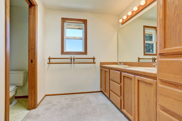 Bathroom interior with wooden vanity cabinet, big mirror and tile floor.