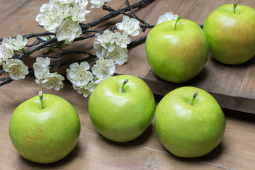 Still life with green apples and blossom on wooden background.