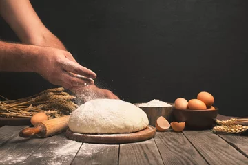Selbstklebende Fototapeten Men hands sprinkle a dough with flour © kucherav