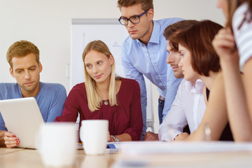 team im büro schaut auf ein tablet mit ernsten gesichtern