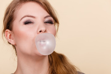 Blonde girl chewing gum making balloon.