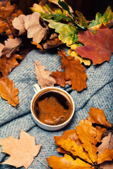 Hot Coffee cup with autumn leaves over wooden background. Abstra