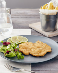 Fried chicken breast fillet on a gray plate with fries. Country style