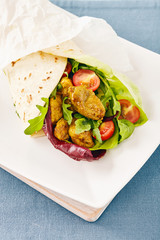 pork wraps on a white serving plate with rocket and lettuce, pastel colors