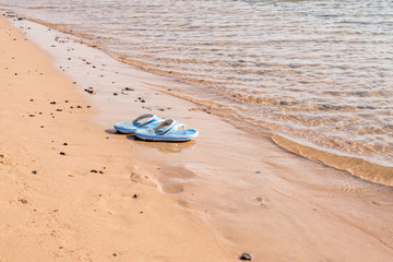 Fototapeta na wymiar Beach shoes on a sandy beach in front of the sea
