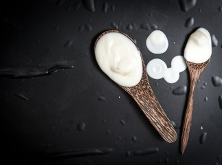 Wooden spoon with milk cream on a black slate