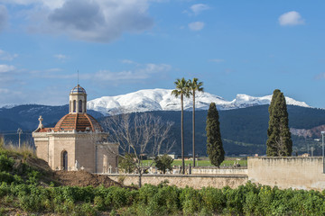 SPAIN, MALLORCA, 2015-02-07: Chapel and cemetery of Sa Pobla in front of the snow covered mountains...