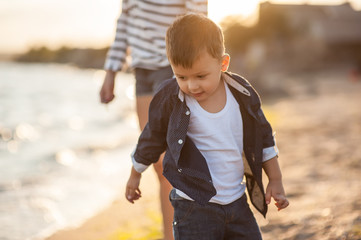 Beautiful boy with a woman relaxing on the beach. Throw pebbles into the sea, running, jumping,...