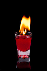 Burning Red cocktail in shot glass on black background