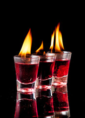 Burning Red cocktail in shot glass on black background