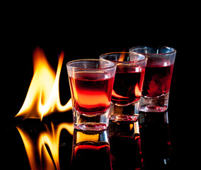 Burning Red cocktail in shot glass on black background