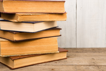 Old and used hardback books or text books on wooden background