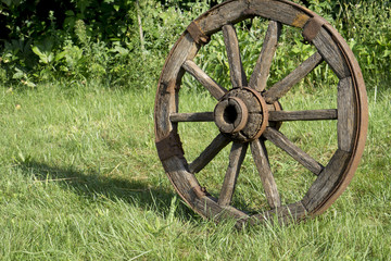Fototapeta na wymiar wooden wheel on a background of green grass