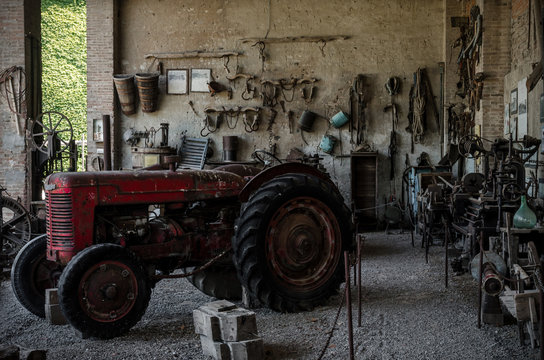 Old tractor in a farmhouse and tools on the wall