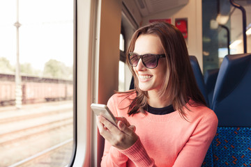 Attractive young woman using her smartphone on a train. 