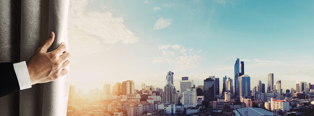 Hand of businessman opening curtain with Bangkok cityscape view in sunrise morning in Thailand