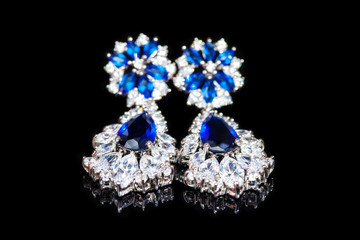 Earrings with blue stones isolated on black, close-up