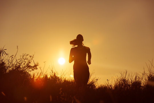 Female runner running at sunset.