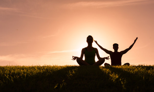 Young couple meditating outdoors. 