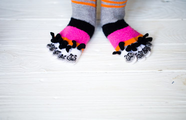 Baby feet in warm, long multicolored socks with toes