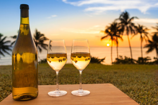 Pair of wine glasses and bottle of wine on a beautiful tropical beach. 