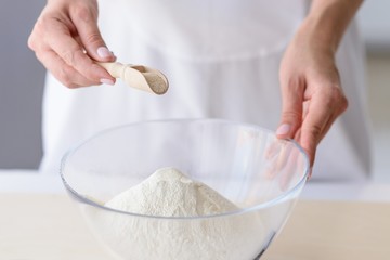 Fototapeta na wymiar Woman adding powdered yeast to flour