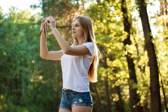 Beautiful young girl taking pictures in the forest. The girl wit