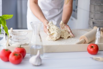 Woman kneading pizza dough on wooden pastry board