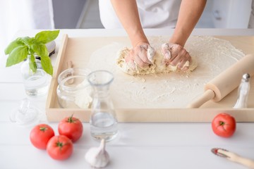 Obraz na płótnie Canvas Woman kneading pizza dough on wooden pastry board