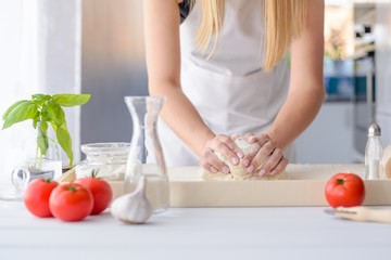 Obraz na płótnie Canvas Woman kneading pizza dough on wooden pastry board