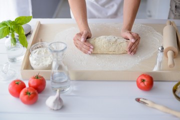 Fototapeta premium Woman kneading pizza dough on wooden pastry board