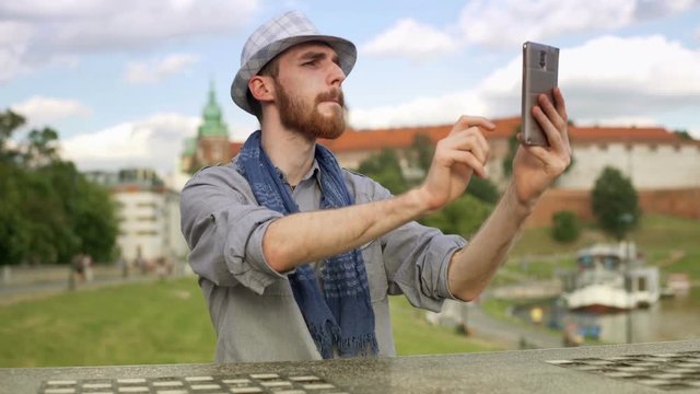 Tourist doing selfies on smartphone while sitting next to the castle
