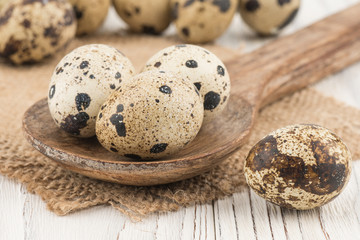 Quail eggs in a wooden spoon and an old wooden table.