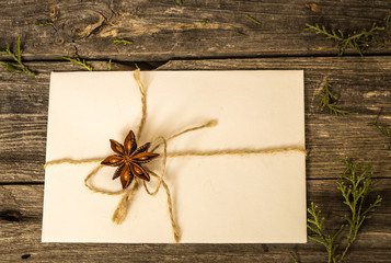 White envelope on wooden background with pine cones and Christmas gift