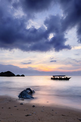 Long exposure. Boat in the sea at pictureous cloudy sunset. Sand