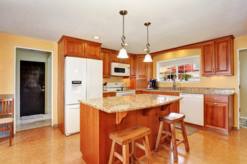 Kitchen room interior with island, wooden cabinets and granite counter top.