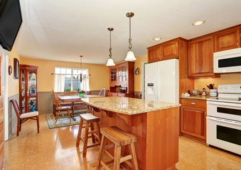 Kitchen room interior with island, wooden cabinets and granite counter top.