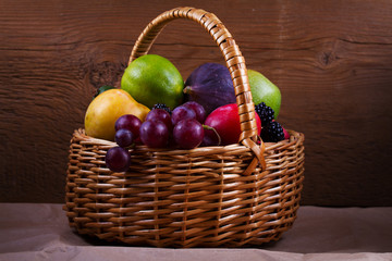 Figs, lemon, lime, plums, grape, blackberries, avocado, apples, pears and peaches in basket. Studio shot of fruits. Fruit still life